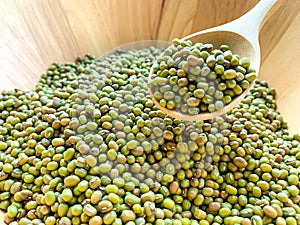 Many mungbean or green beans on a wooden spoon in a wooden bowl photo