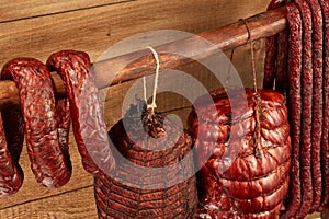 Many natural sausage and ham hanged on wooden stick