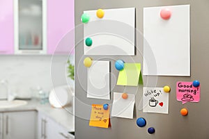 Many notes and empty sheets with magnets on refrigerator door in kitchen