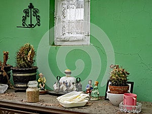 Many objects on a sideboard against a green wall