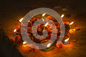 A many oil burning candles in a circle with fresh flowers and smoking incense sticks at night time celebrating Diwali