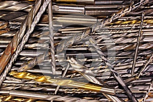 Many old dirty used metal drill bits as background