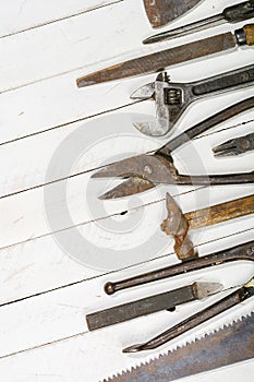 Many old rusty tools scattered on the wooden tstolu. View from above.