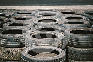 Many old used car tires stacked on top of each other on Automobile sports complex. Industrial landfill for the