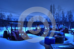 Many old vibrant weathered tractors in snowy parts yard