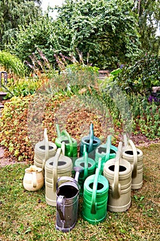 Many old watering cans in a garden