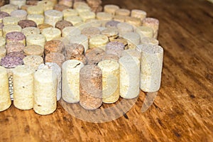 Many old wine corks stand on wooden background side