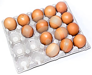 Many orange farm spotted brown chicken eggs in carton open box container on white backdrop. View from the top