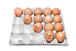 Many orange spotted brown chicken eggs in carton open box container on white background. Three eggs with emotion faces