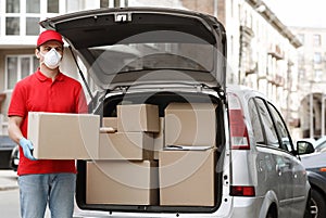 Many orders, a lot of deliveries concept. Courier holds big parcel near the car photo