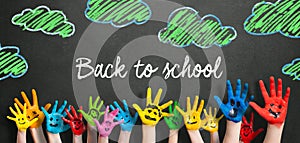 Many painted kids hands with smileys and the message `Back to school`