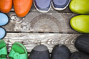 Many pairs of summer shoes: Rubber boots, slippers, galoshes on a vintage wooden floor,