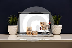 Many paper boxes in a small shopping cart on a laptop keyboard. Concepts about online shopping that consumers can buy