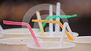 Many paper cups with straws on table, alcoholic beverages at teenage party