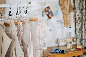 Many paper sewing patterns for different clothes hanging on the rack in sewing factory background. Clothing pattern