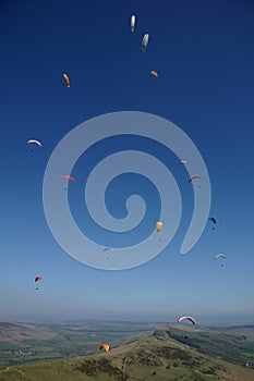 Many para-gliders over a green landscape photo