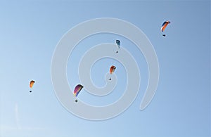 Many paragliders simultaneously is flying in a clear blue sky