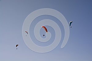 Many paragliders simultaneously is flying in a clear blue sky