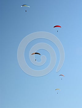 Many paragliders simultaneously is flying in a clear blue sky