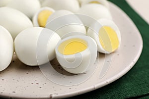 Many peeled hard boiled quail eggs on plate, closeup