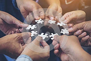 Many people hands holding a jigsaw puzzle in circle together