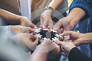 many people hands holding a jigsaw puzzle in circle together