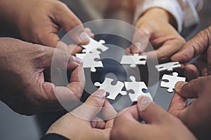 Many people hands holding a jigsaw puzzle in circle together