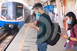 Many people are wearing surgical masks and waiting to board the public train at rush hour