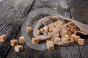 Many pieces of brown sugar on a wooden background. Heap of brown sugar cubes on wooden table, closeup