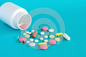 Many pills are poured from a medicine bottle. Pills and pills on a blue background. Medical tablets: analgesics