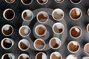 Many plastic cups with tasty aromatic coffee on dark background, flat lay