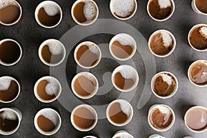 Many plastic cups with tasty aromatic coffee on dark background, flat lay