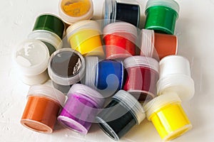 Many plastic jars with gouache or acrylic paints top view on a light background. Selective soft fokus. Text copy space