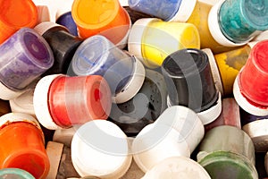 Many plastic jars with gouache or acrylic paints top view on a light background. Selective soft fokus. Text copy space