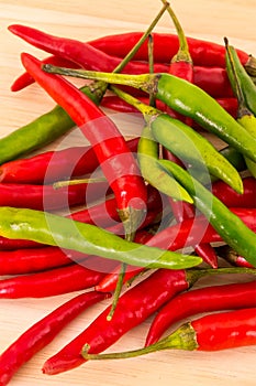 Many pods of long chili peppers green red contrasting fruits base bright contrasting on a wooden base