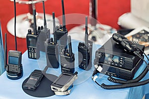 Many portable radio transceivers on table at technology exhibition. Different walkie-talkie radio set. Communication devices photo