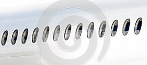 Many portholes in a row on the fuselage of a white airplane.