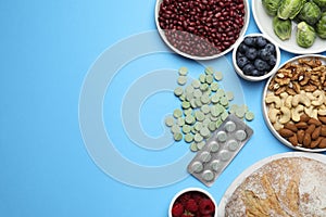 Many prebiotic pills and food on light blue background, flat lay. Space for text