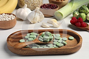 Many prebiotic pills and food on white wooden table