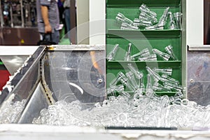 Many preform plastic pet transparent raw material in metal bucket during transport by inclined step conveyor for automatic