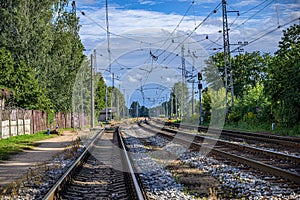 Many railway tracks stretching to the horizon; the woods, the fence, sky and the wires