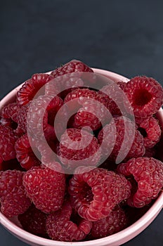 Many raspberries in a plate on a black background Stacked image Still life photography