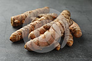 Many raw turmeric roots on grey table, closeup