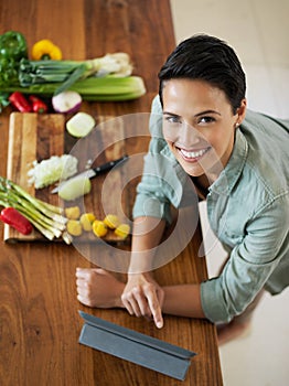 So many recipes at a touch of my fingertips. Portrait of a smiling young woman using a digital tablet while preparing a