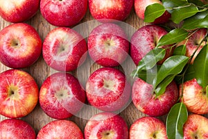 Many red apples with leaves on a wooden background