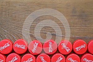 Many red caps with coca cola logo on wooden background