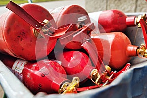 Many red fire extinguishers are lying in stack. Fire extinguishing equipment. Distribution of fire extinguishers for