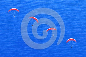 Many red parachutes in the sky above the blue sea. Image in the style of minimalism.