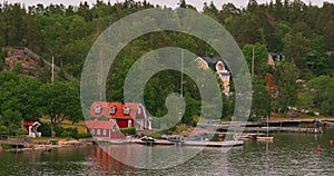 Many Red Swedish Wooden Sauna Logs Cabins Houses On Island Coast In Summer Cloudy Day. Swedish Old Tradition Wooden