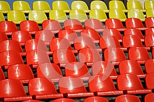 Many red and yellow plastic seats in an open stadium. Free access. Empty seats, without spectators. Waiting for the spectacle